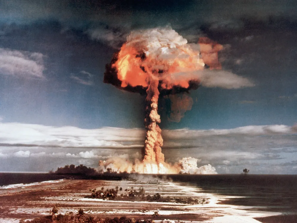 A mushroom cloud rises above a Pacific atoll during a 1950s atomic bomb test.